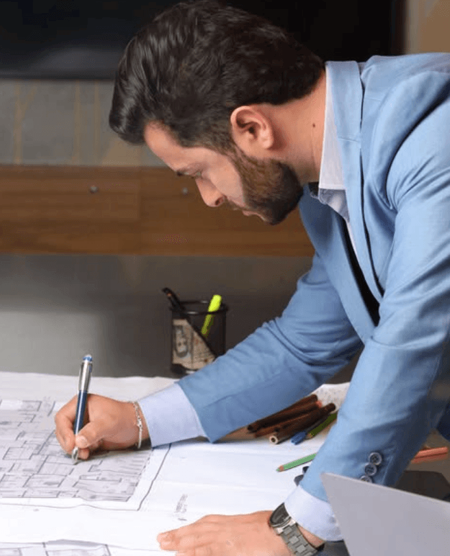 Weverton in a blue shirt, drawing architectural plans