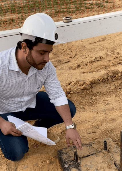 Weverton wearing a hard hat onsite, reviewing architectural drawings